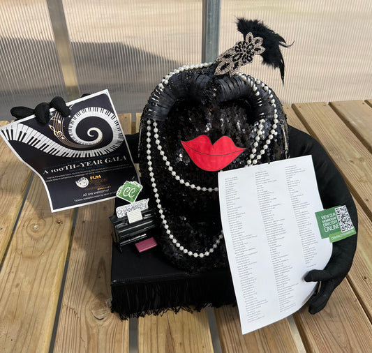 Pumpkin wrapped in a black sequins with arms added holding the Gala Event flier.